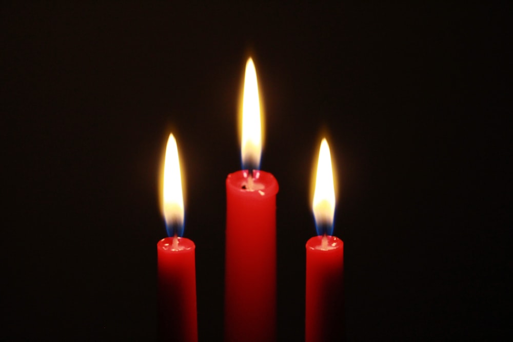 three red candles are lit in the dark