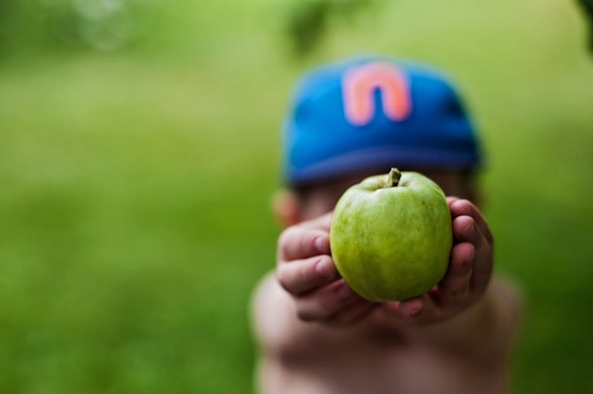 a person holding a green apple in their hand