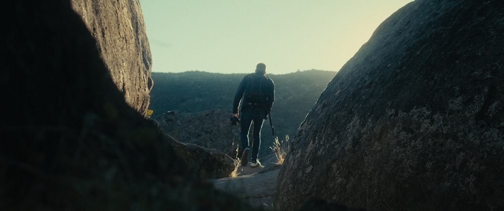 a man standing in between two large rocks