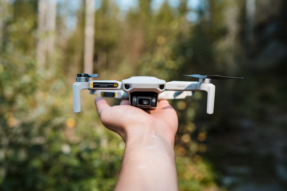 a person holding a small white and black remote controlled flying device