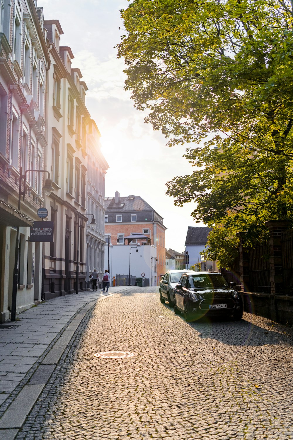 a car is parked on a cobblestone street