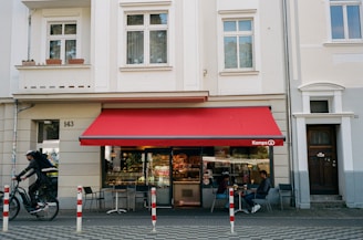 a man riding a bike past a red awning