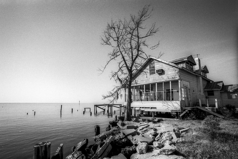 uma foto em preto e branco de uma casa à beira da água