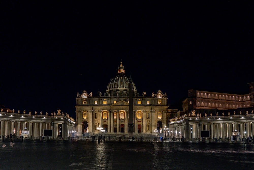 a building lit up at night with a fountain in front of it