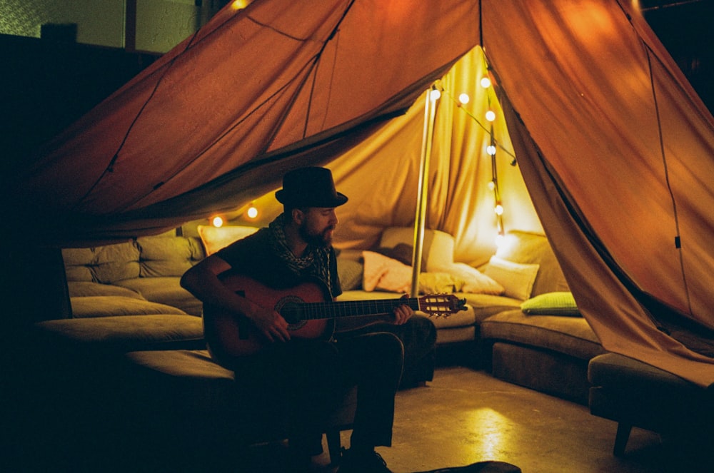 a man playing a guitar inside of a tent