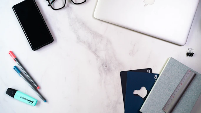 A bright, clean workspace with a phone, notebook, and a bottle of Kleenex9 cleaning product on the desk.