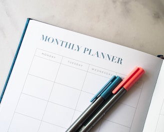 a planner with two pens sitting on top of it