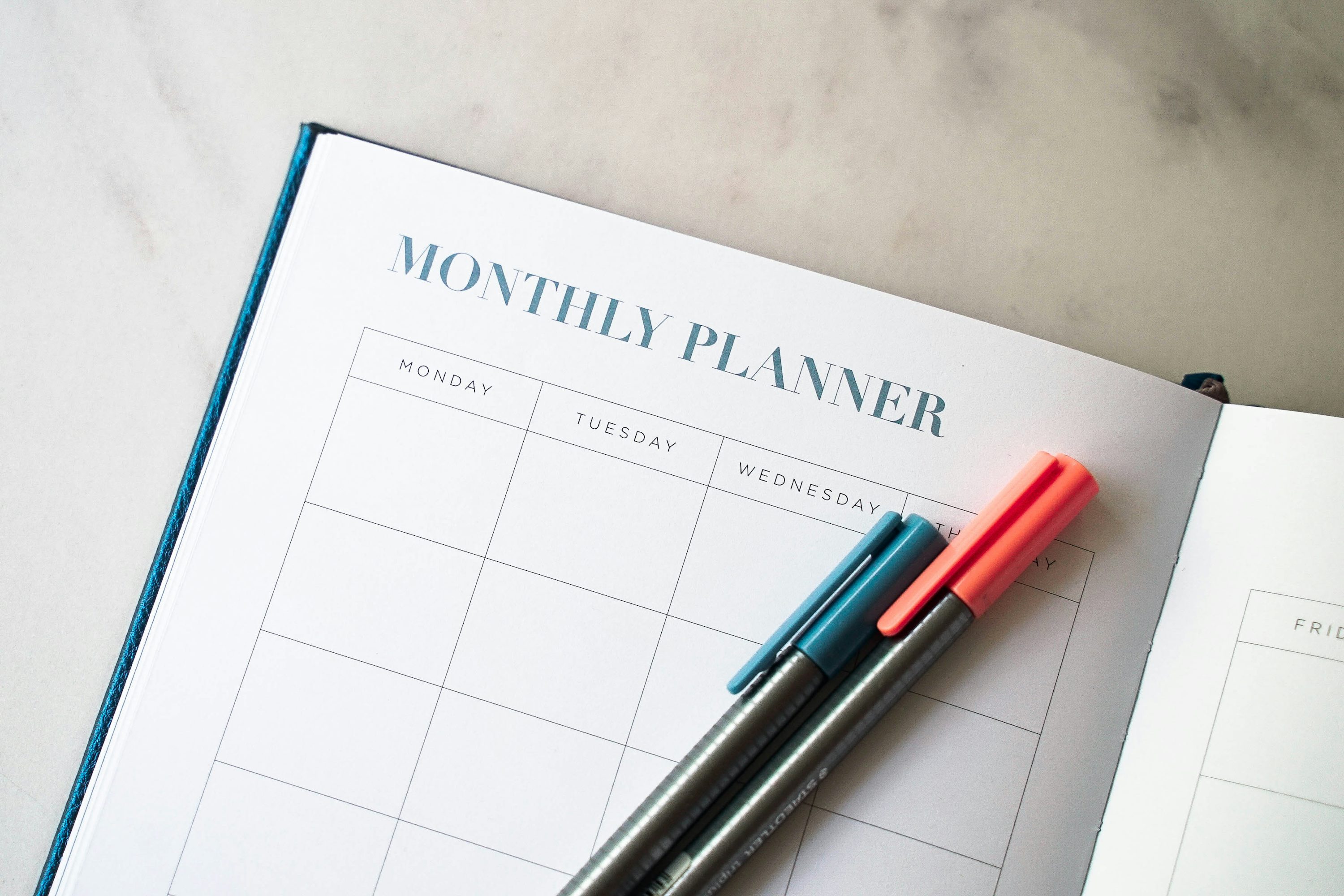 60 Monthly Goal Ideas to Set in the Start of Every Month 3 a goal planner with two pens sitting on top of it