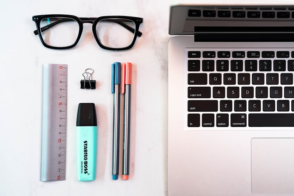 a laptop computer sitting next to a pair of glasses