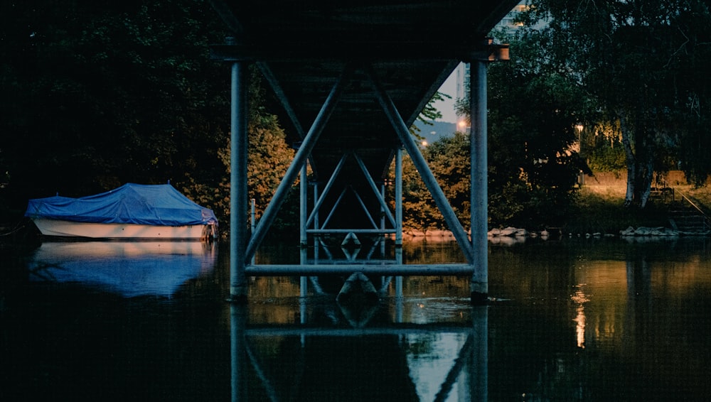 a boat sitting under a bridge at night