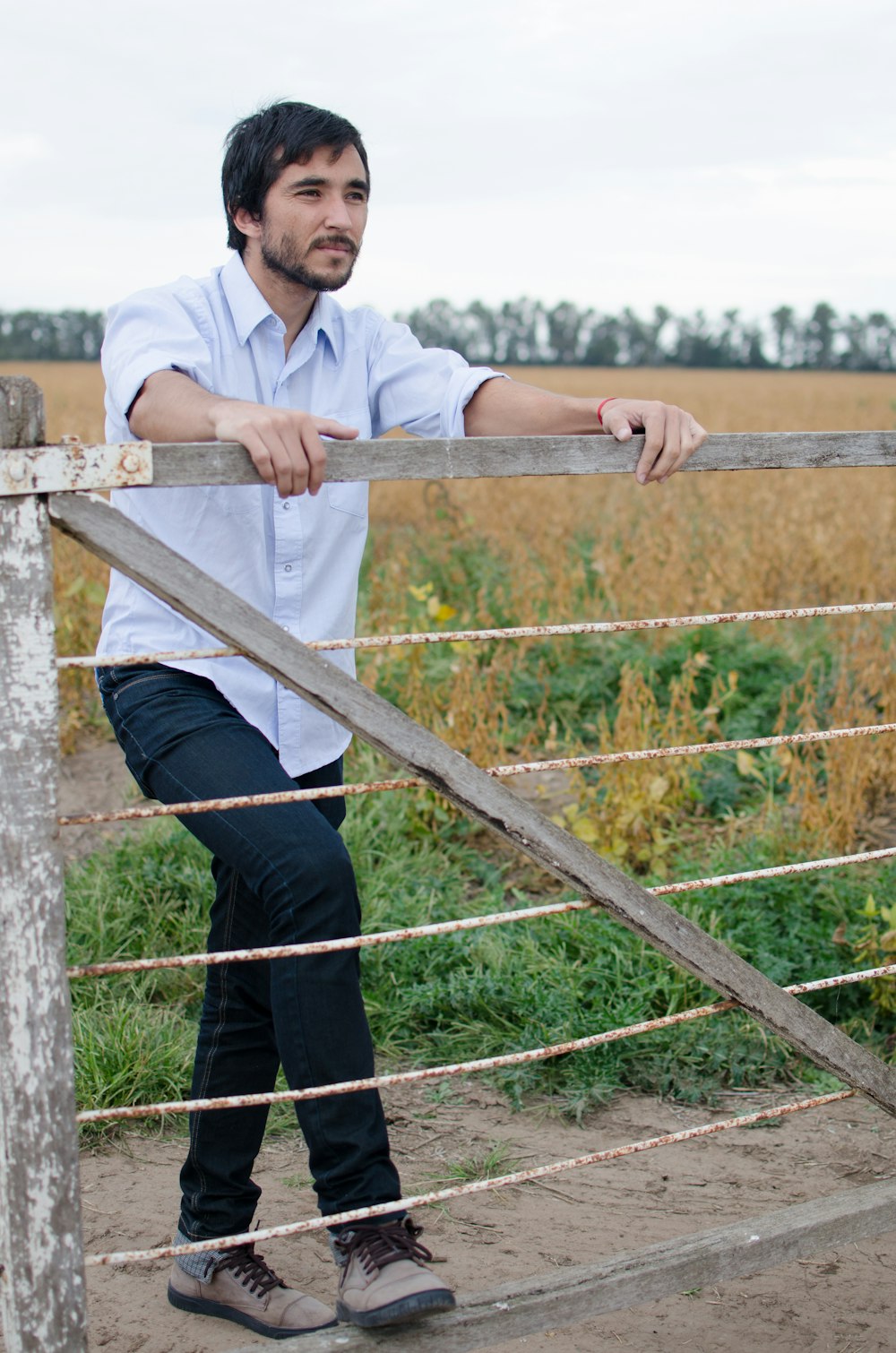 a man leaning on a fence in a field