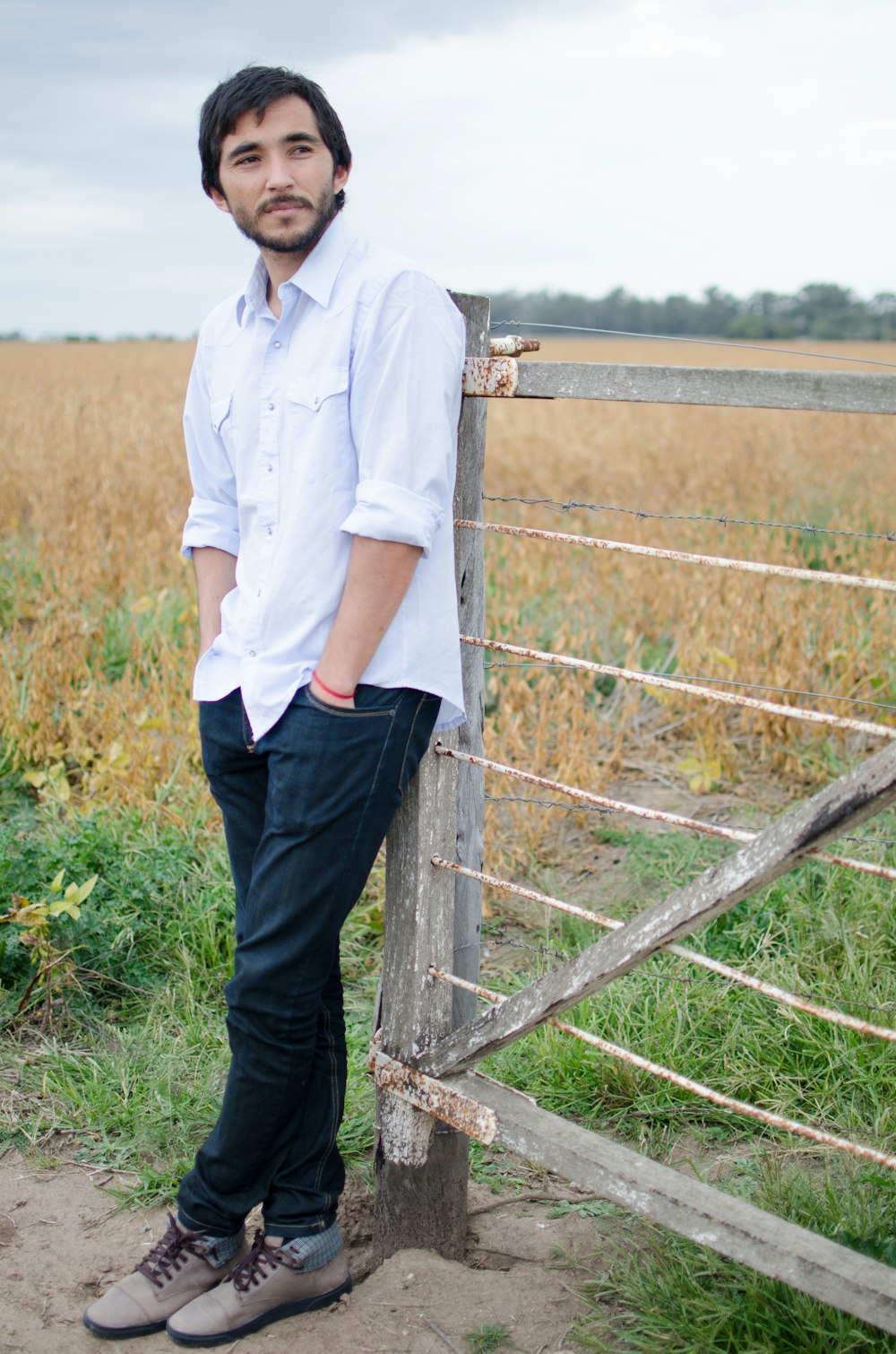 a man leaning against a fence in a field