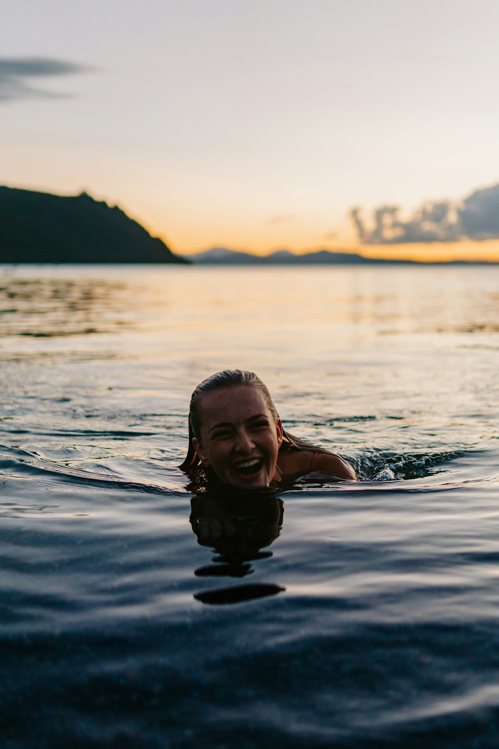 a woman swimming in the ocean at sunset