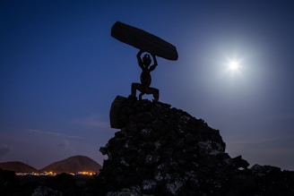 a statue of a man holding a surfboard on top of a pile of rocks