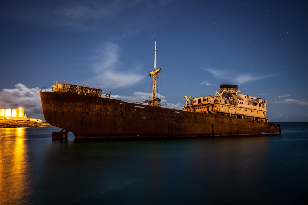 Una grande nave arrugginita seduta sopra uno specchio d'acqua