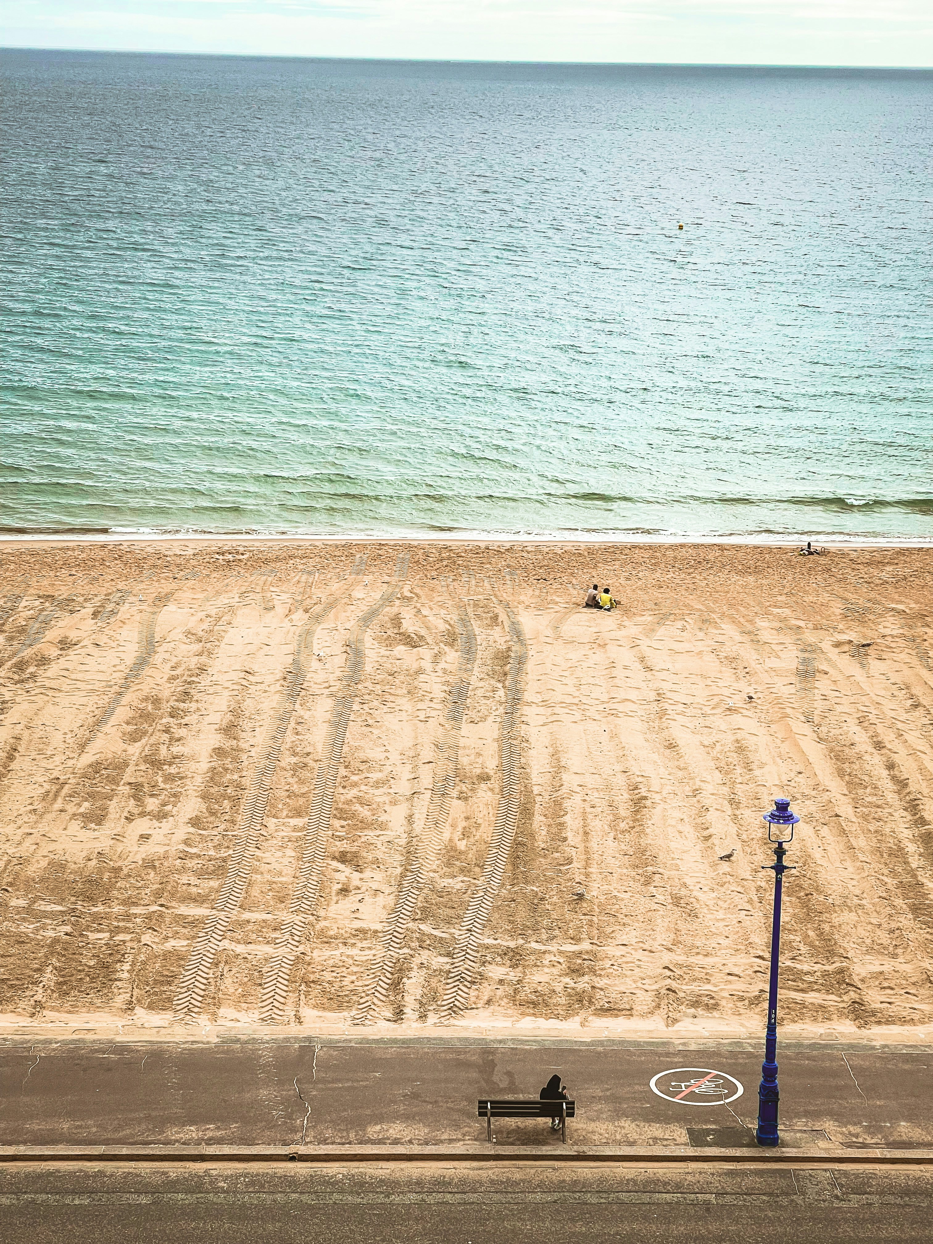 a beach with a bench and a street light