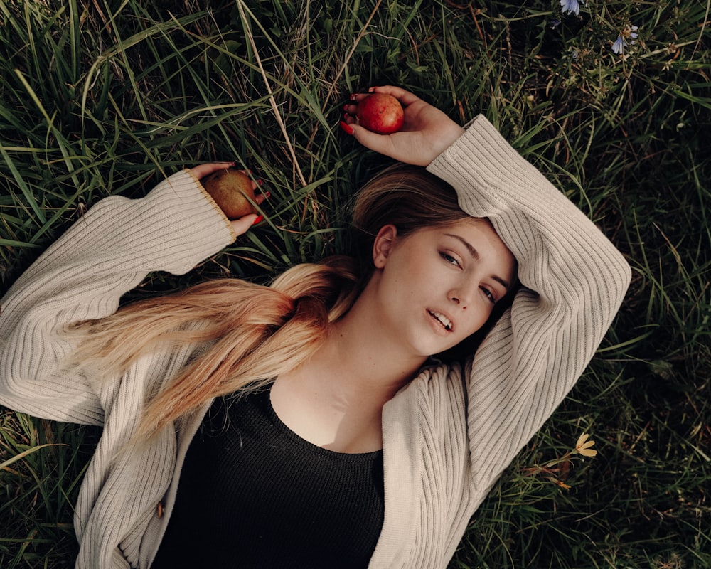 a woman laying in the grass with an apple