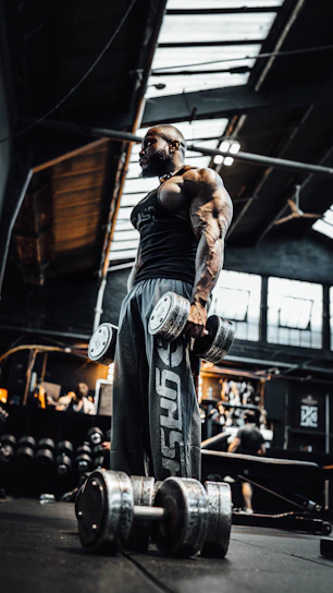 Close-up of a male athlete gripping heavy barbells in a dimly lit gym.