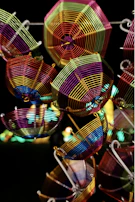 A variety of wireforms displayed on a wooden table, showcasing intricate bends and shapes.