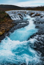 a stream of water running through a lush green field