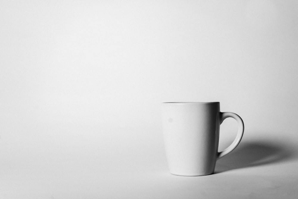 a white coffee cup sitting on top of a table