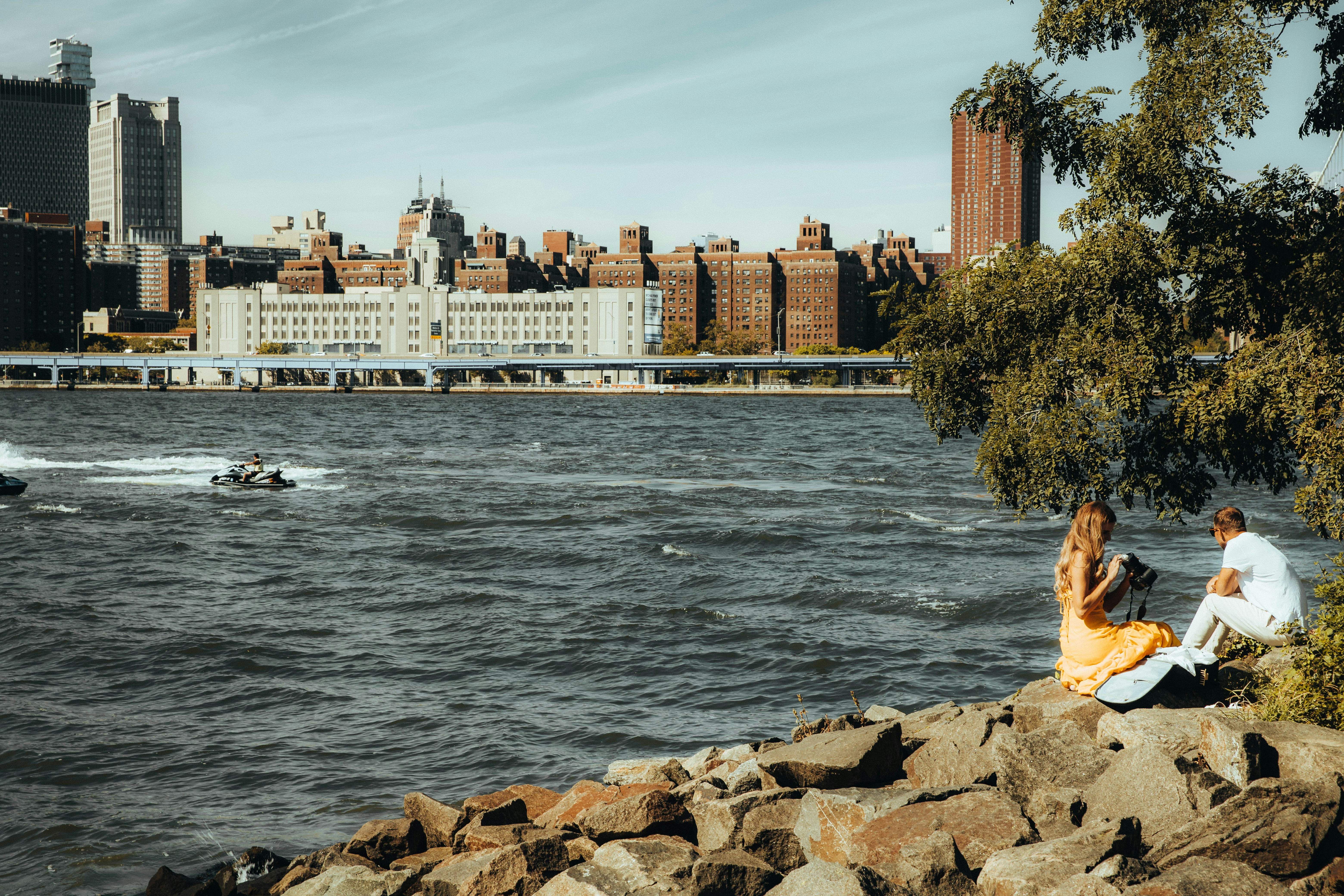 a man and a woman sitting on rocks near the water