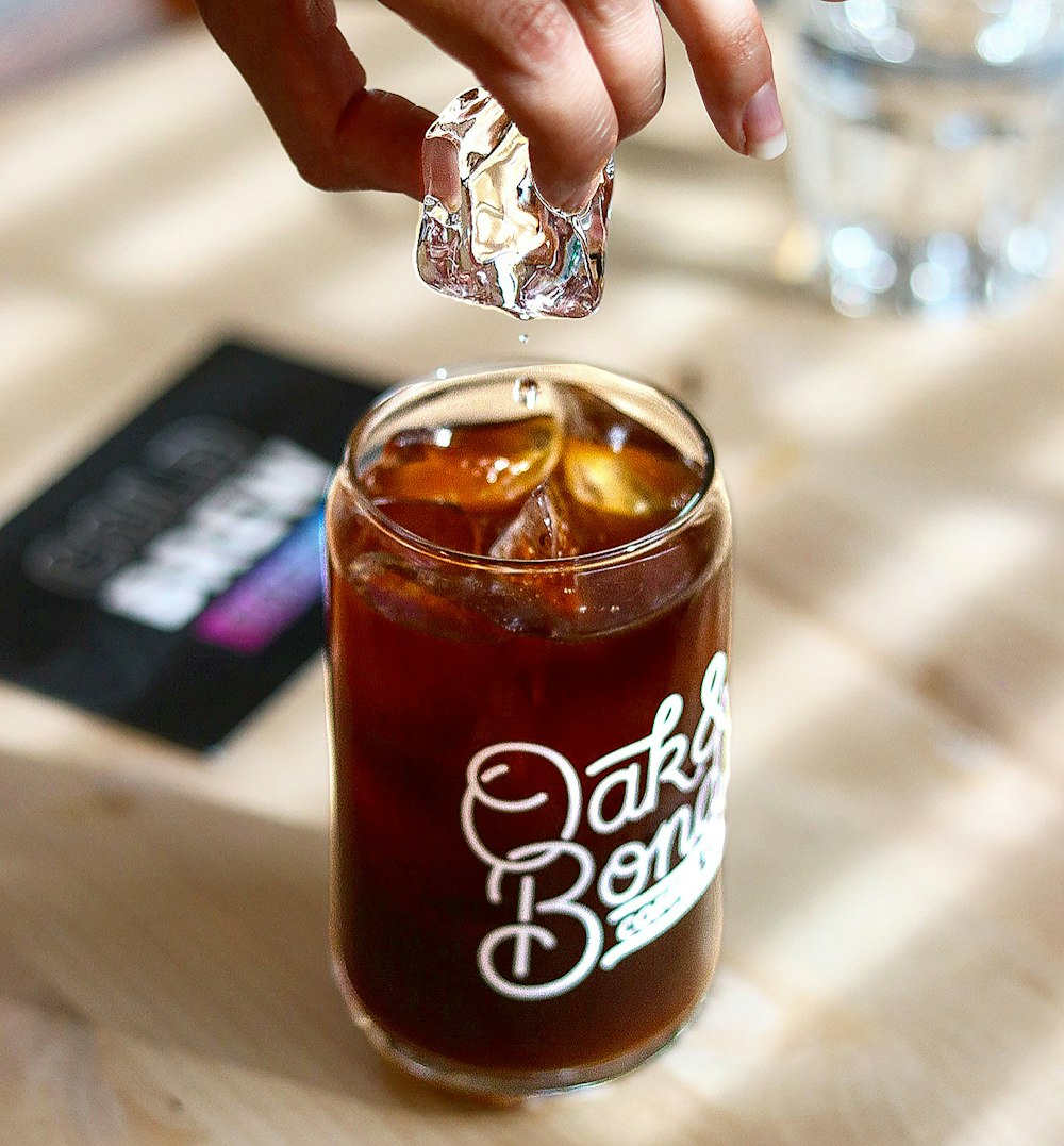 a person holding a piece of foil over a drink