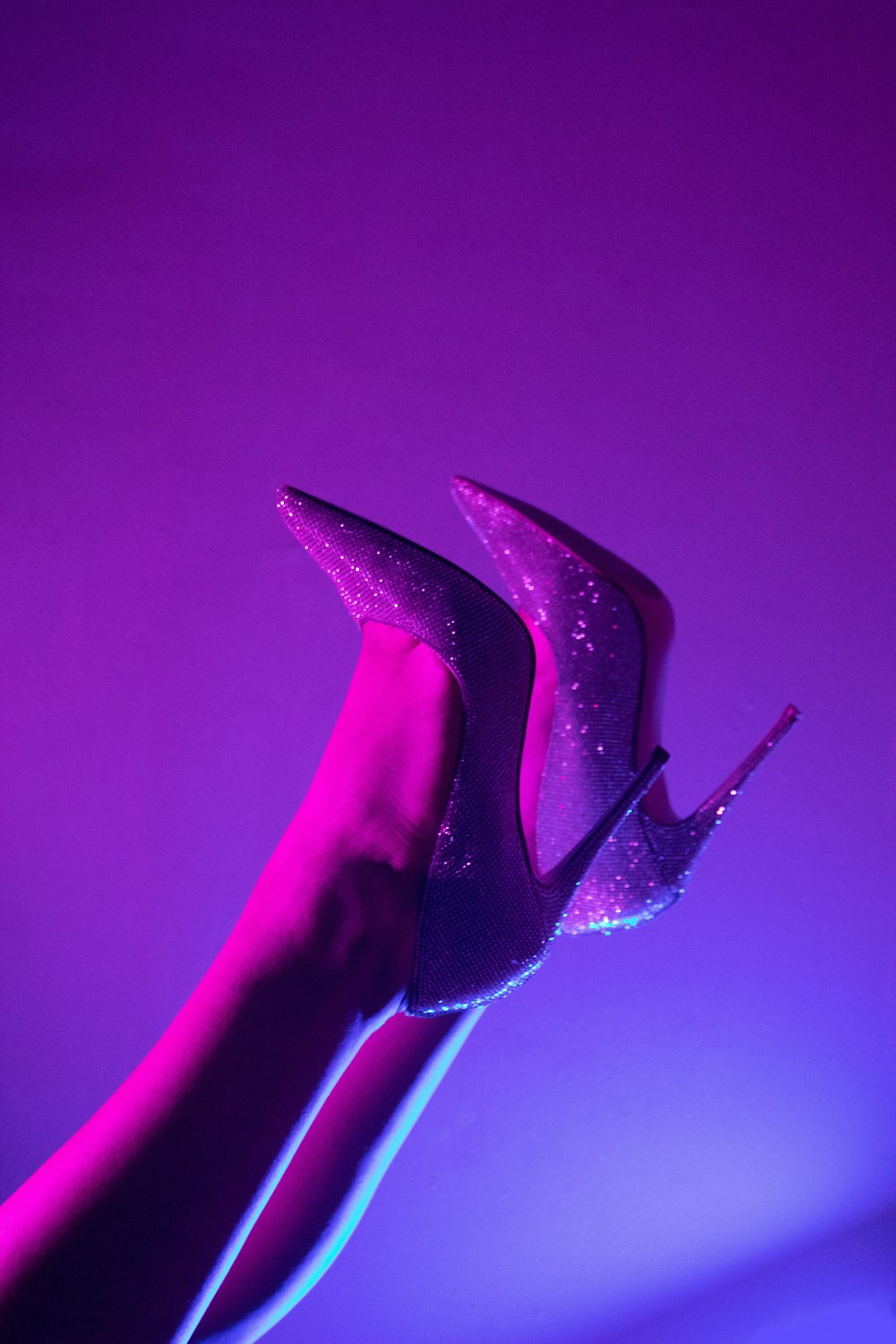 ein Paar lila Schuhe mit hohen Absätzen am Bein einer Frau