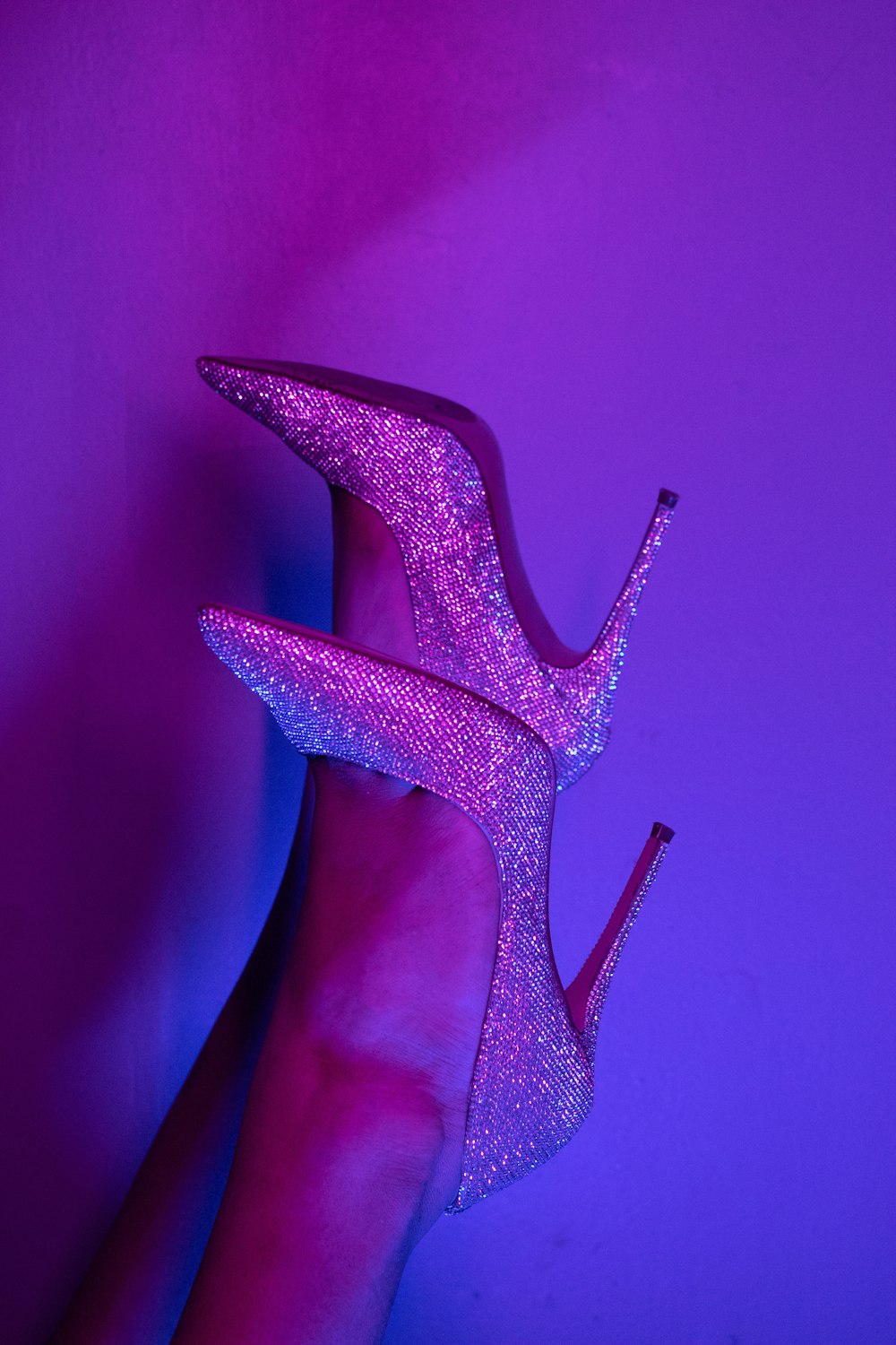 a woman's hand holding a purple high heel shoe