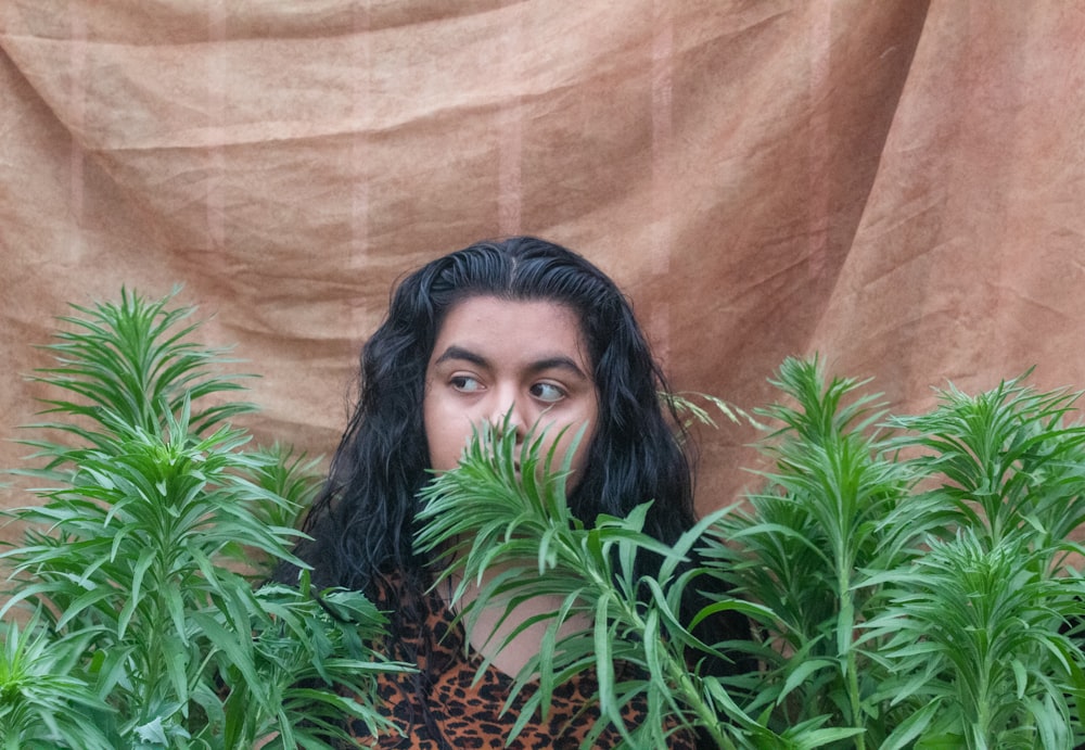 a woman with long hair hiding behind plants