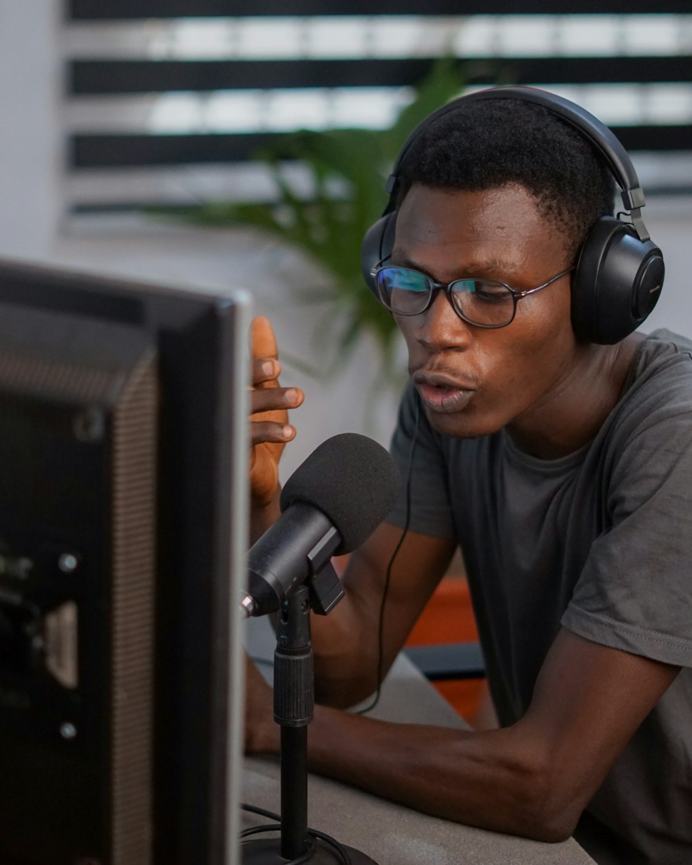 um homem usando fones de ouvido e um microfone na frente de um computador