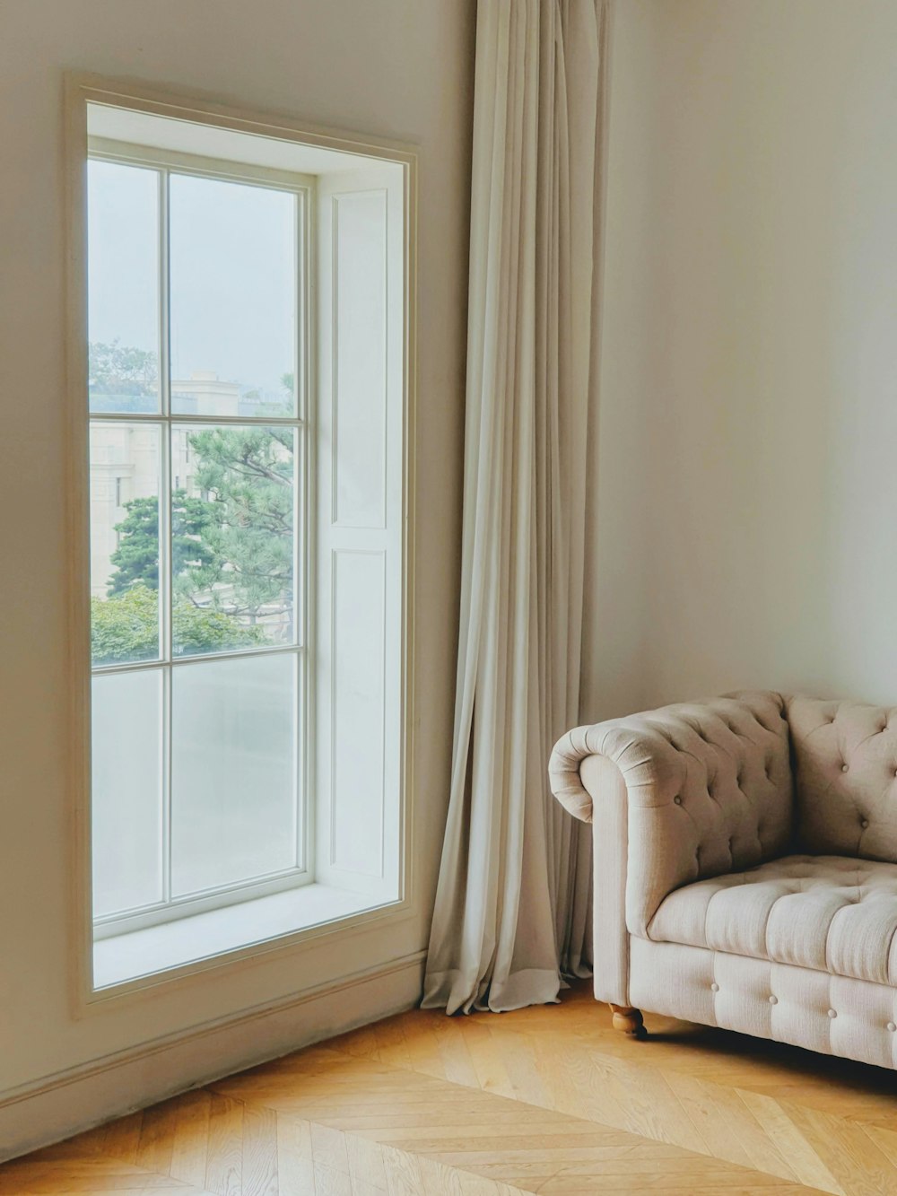 eine weiße Couch in einem Wohnzimmer neben einem Fenster