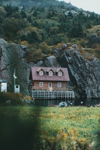 a red house sitting on top of a lush green hillside
