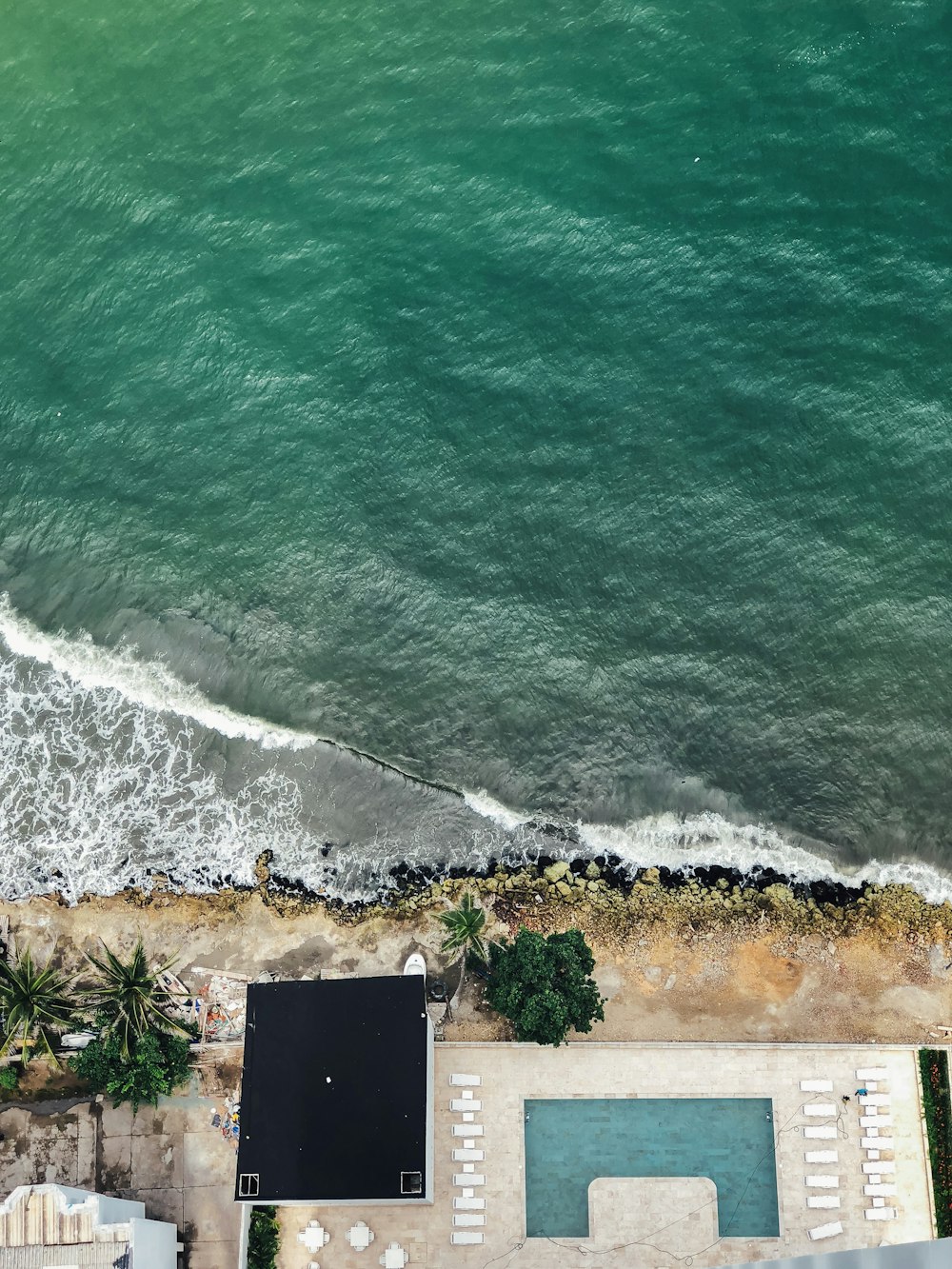 an aerial view of a beach with a swimming pool