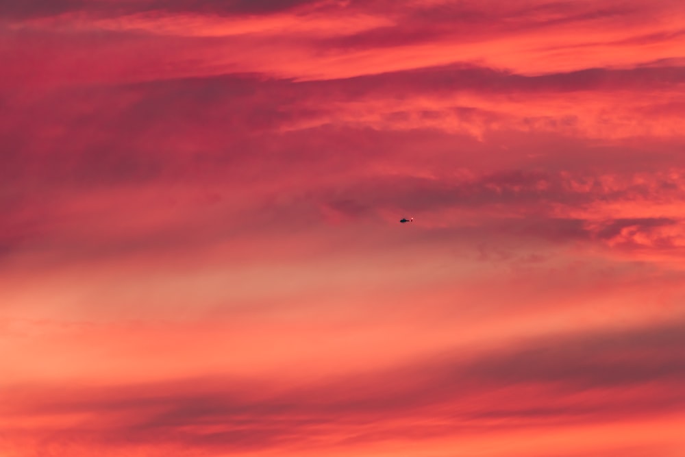 a plane flying in the sky at sunset