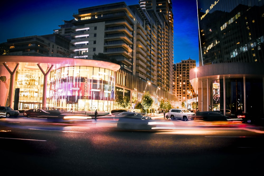 a city street at night with cars passing by