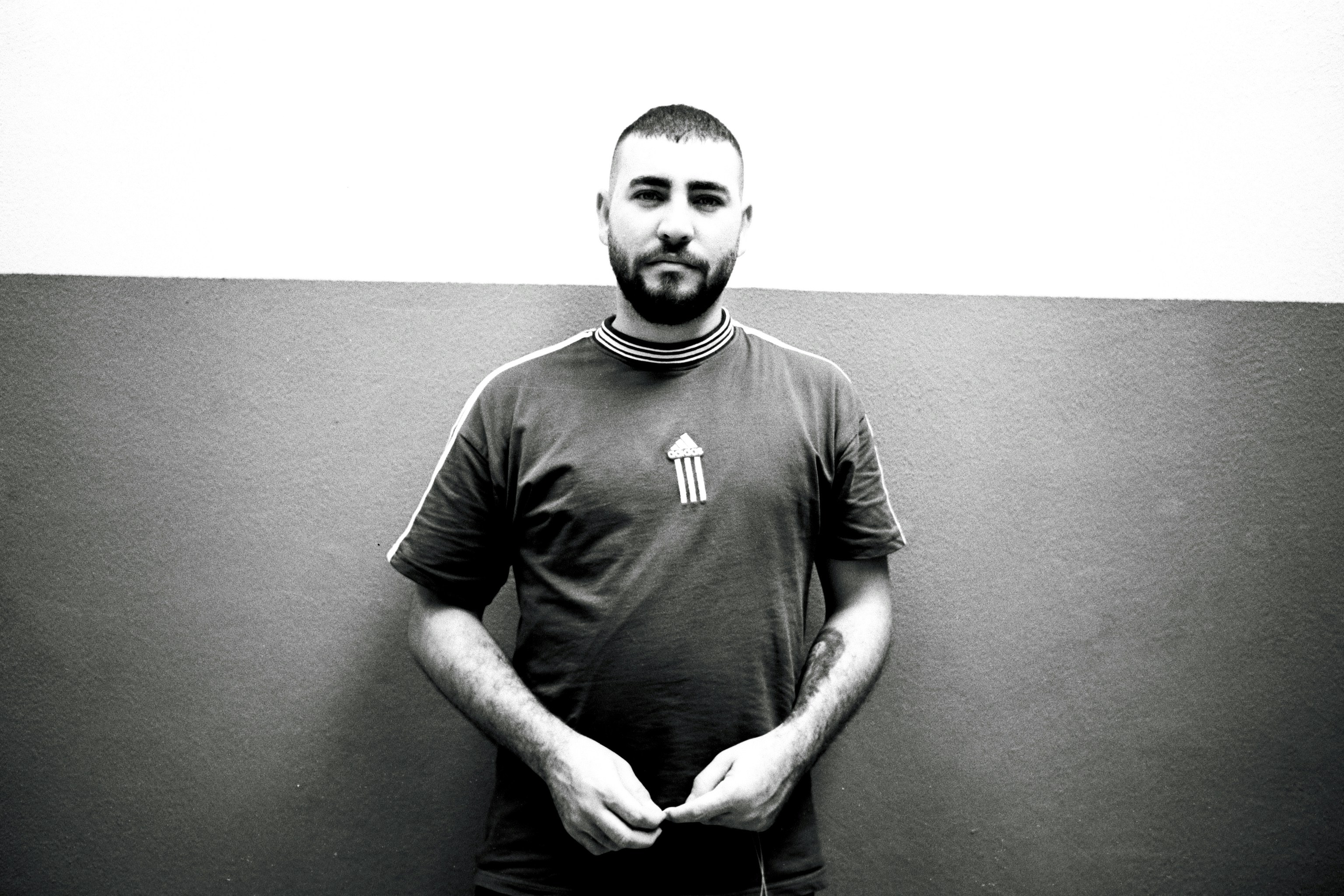 a man standing in front of a wall with his hands in his pockets