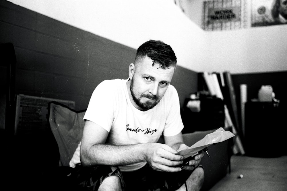 a man sitting on the floor looking at a piece of paper