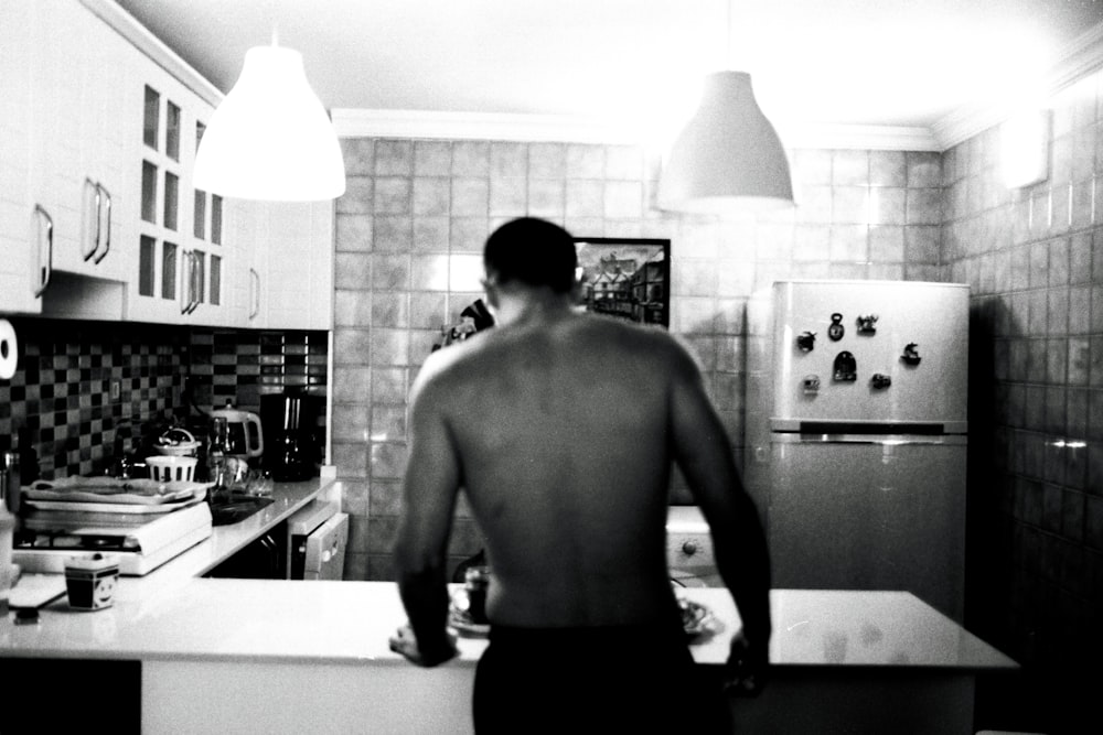 Un hombre parado en una cocina junto a un refrigerador