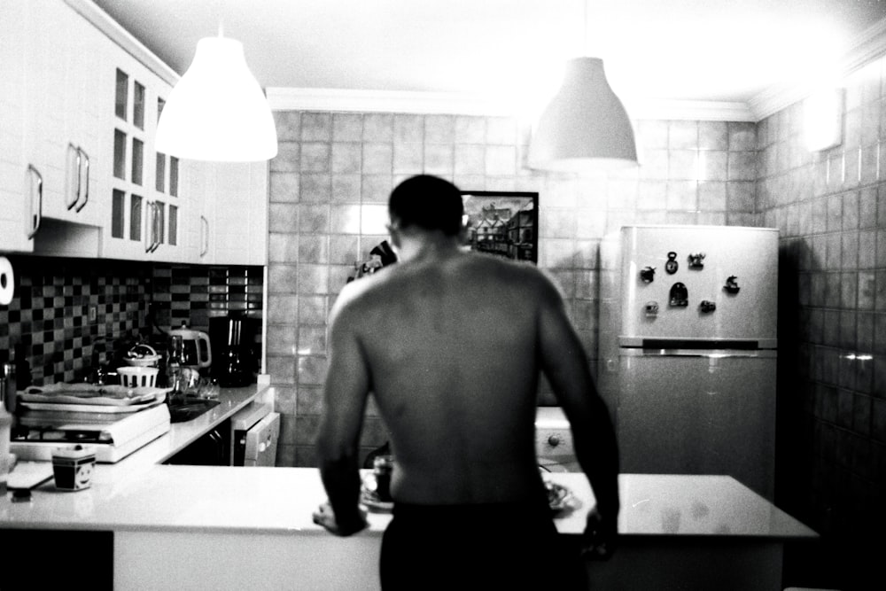 a man standing in a kitchen next to a refrigerator