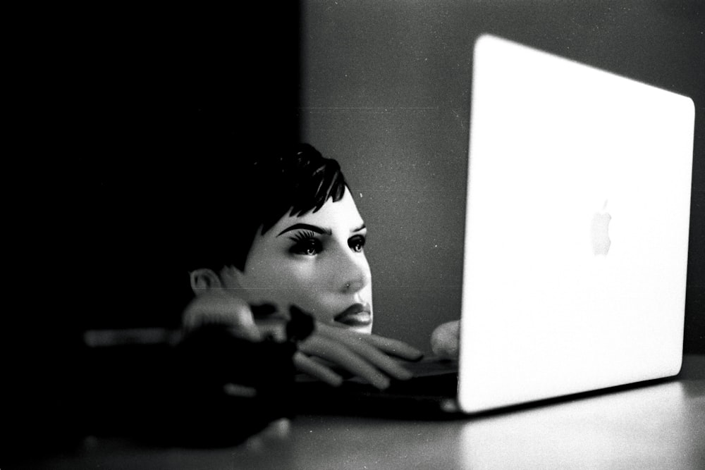 a black and white photo of a woman using a laptop