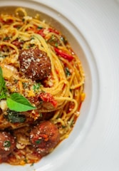 a white plate topped with spaghetti and meatballs