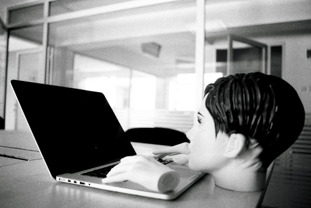 a young boy sitting in front of a laptop computer