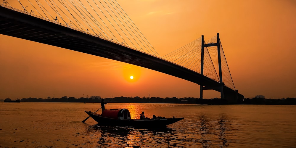 a boat floating on top of a river under a bridge