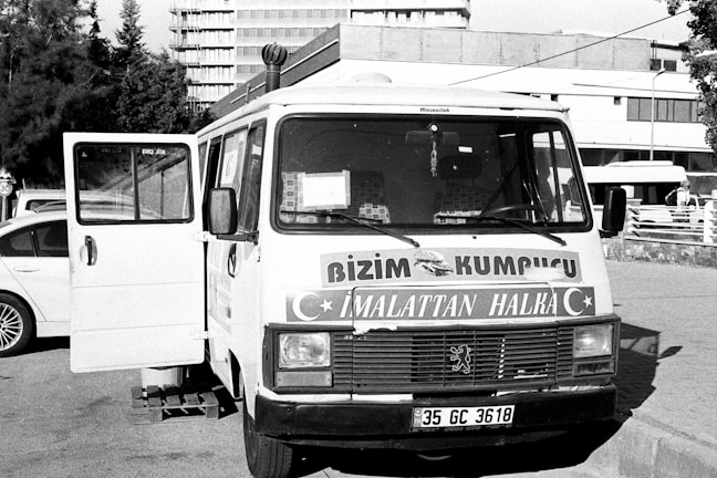 A polished delivery van parked near a busy marketplace, ready for service.