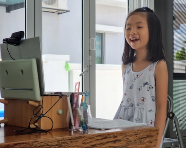 a little girl standing in front of a computer