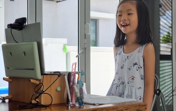 a little girl standing in front of a computer