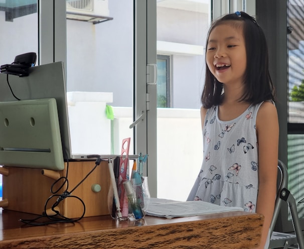 a little girl standing in front of a computer