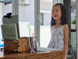a little girl standing in front of a computer