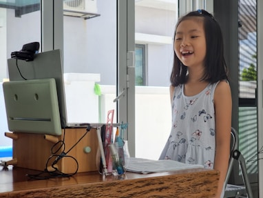 a little girl standing in front of a computer
